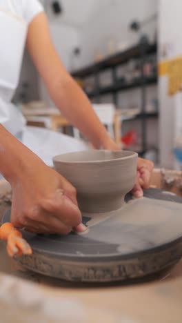 close-up of hands shaping a clay bowl on a pottery wheel