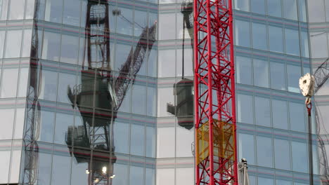 grúa del sitio de construcción que se refleja en la fachada del edificio de oficinas moderno