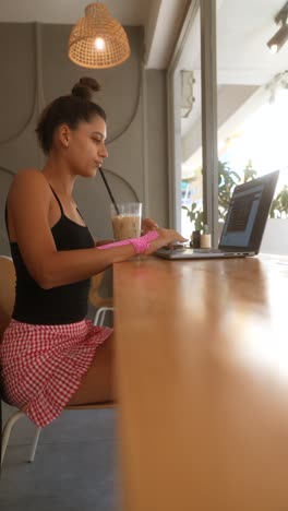 mujer trabajando en una computadora portátil en un café