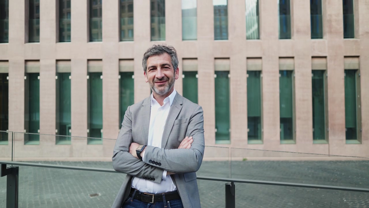 Empresario seguro sonriendo con los brazos cruzados frente a un edificio moderno