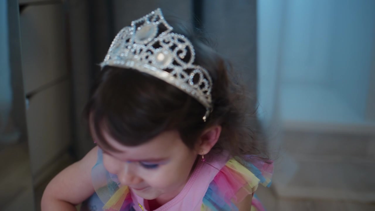 Menina em traje de princesa sorri alegremente. Ela usa tiara e vestido arco-íris. Parecendo feliz, alegre e brincalhona durante uma celebração. Perfeito para eventos de aniversário, festas infantis.