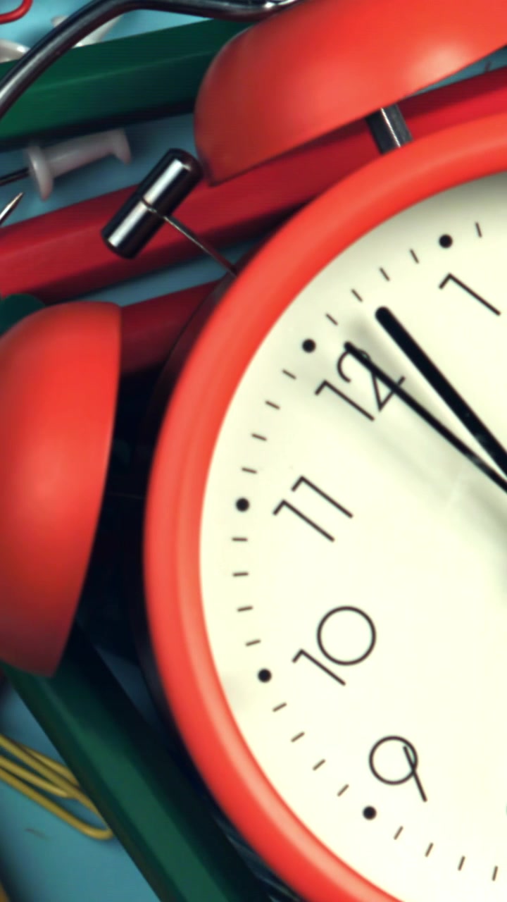 Red Alarm Clock Ticking Amidst Colorful Office Supplies