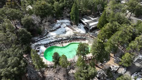 forest falls ca resort in shoulder season algae filled pool amid snow covered landscape aerial orbit 60fps