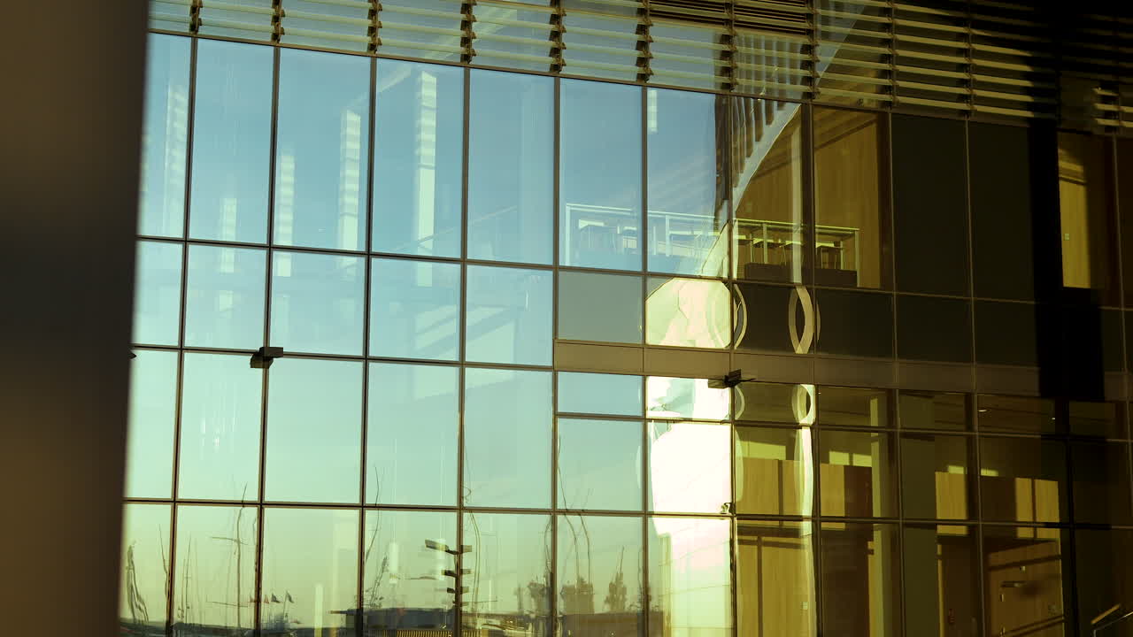 Golden sunlight bathing a modern building's glass facade with blinds and city reflections