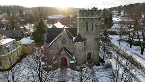 slow aerial tilt up of gothic church building on snowy day with moody sunshine