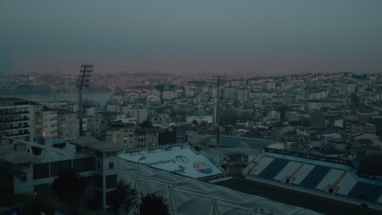 Vista della città di Istanbul al tramonto con edifici e uno stadio.