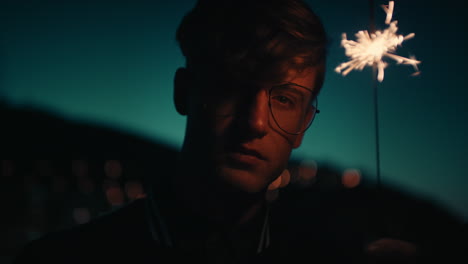 young-man-holding-sparkler-celebrating-new-years-eve-party-at-night