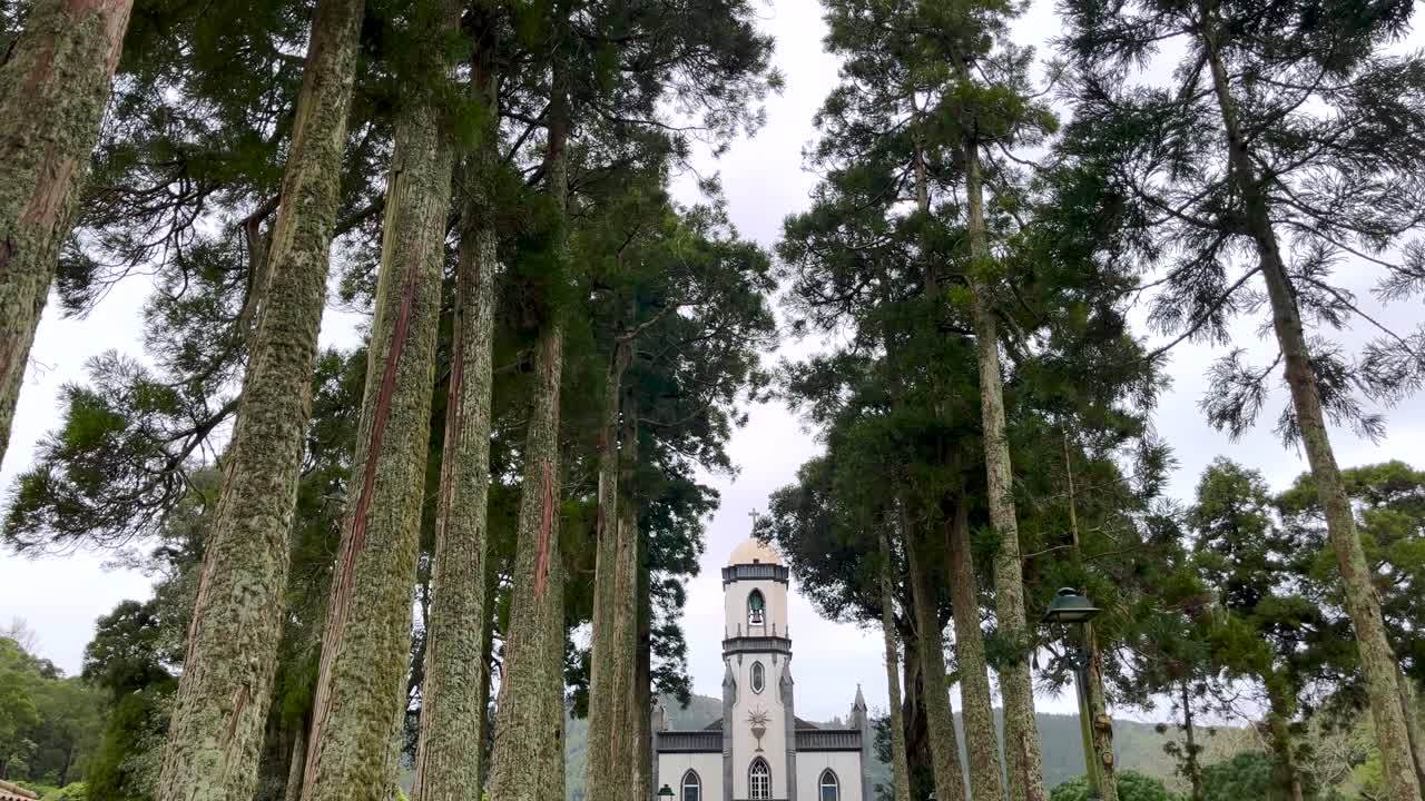 static view of a church surrounded by tall trees. Orbit ascending