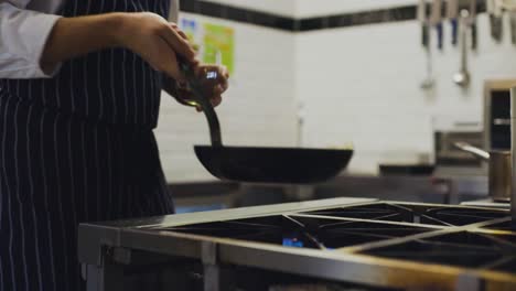 slow motion of chef cooking flipping food in pan in a professional kitchen