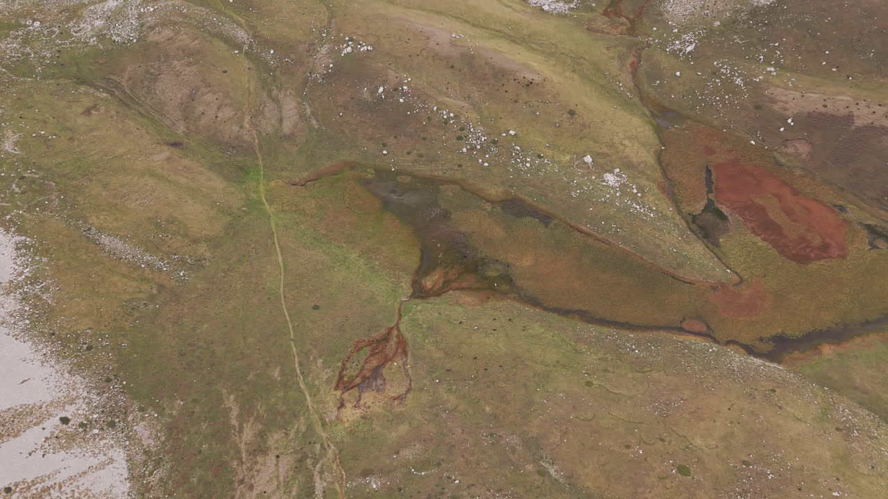Drone overview of winding waterways nestled in rugged cliffs of Mount Tymfi, fog drifting over calm waters