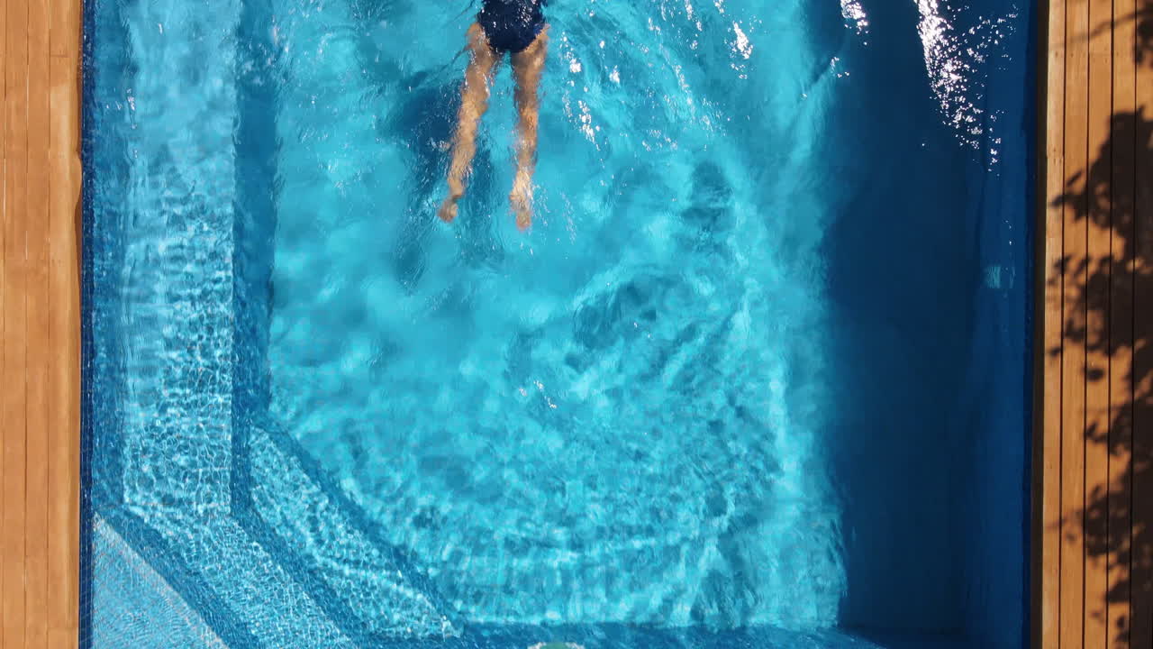 Wanita dengan baju renang biru berenang di kolam renang