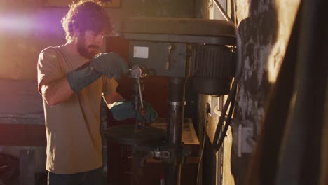 caucasian male blacksmith forging metal tool in workshop