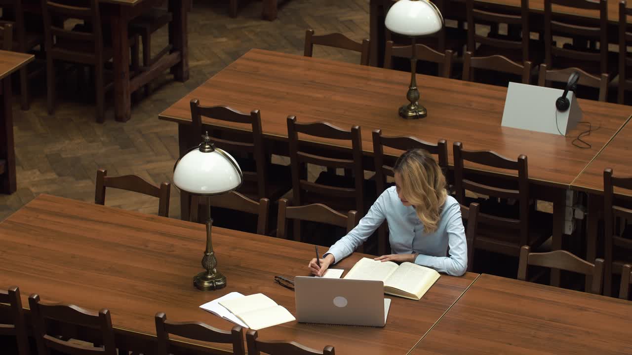 женщина учится в библиотеке.