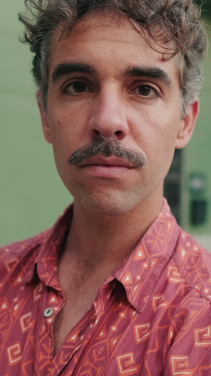 Close-up de um homem com bigode e piercing no nariz