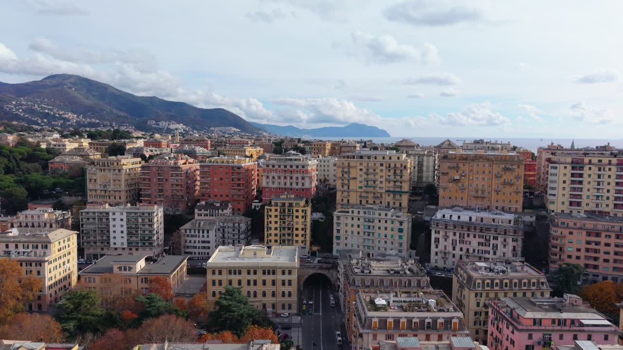 Ripresa aerea con drone sopra Genova con edifici colorati, area portuale e montagne
