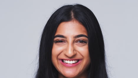 cabeza y hombros foto de estudio de una mujer sonriendo a la cámara en cámara lenta