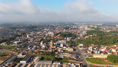 drone pivots from urban sprawl to more vegetated slopes, where trees and clouds soften joinville’s edges. ideal for ecological contrast or regional serenity