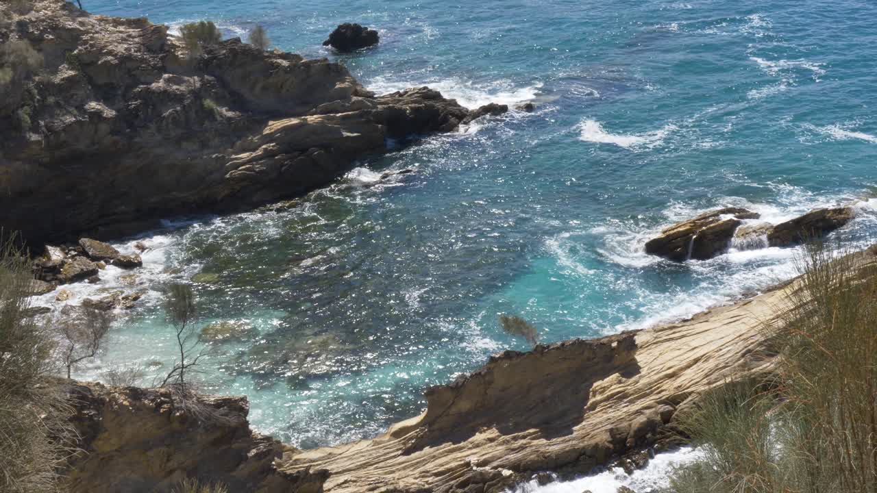 Rallentatore di un paesaggio che mostra l'insenatura oceanica della baia con la barriera corallina, circondata da un promontorio roccioso e da alberi della foresta arbustiva lungo la costa di Malua Bay, South Coast, NSW, Australia, viaggi, turismo e natura