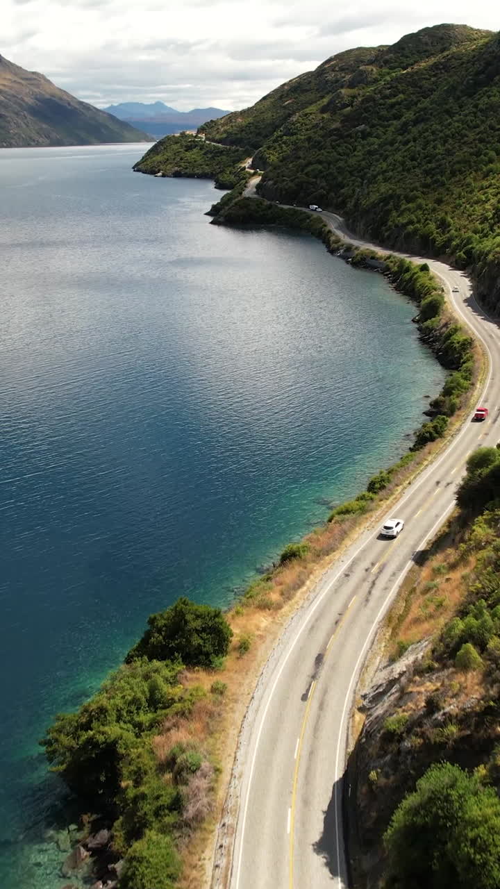 Winding scenic road on Lake Wakatipu to Queenstown. New Zealand journey, road trip. Vertical
