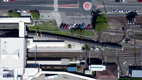 Toma-Aérea-De-Drones-De-Un-Tren-Urbano-Que-Sale-De-Las-Vías-Del-Tren-De-La-Estación-De-Gosford-Con-Plataforma-De-Estacionamiento,-Transporte,-Viajes,-Costa-Central,-Australia-4k