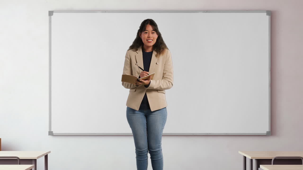 Female Teacher In School Classroom Standing In Front Of Board Taking Class Register