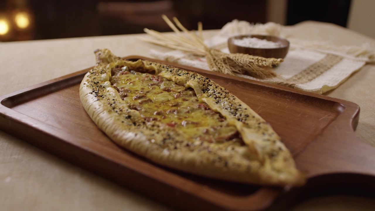 Freshly baked Turkish pide, a traditional flatbread with cheese and meat on a wooden platter