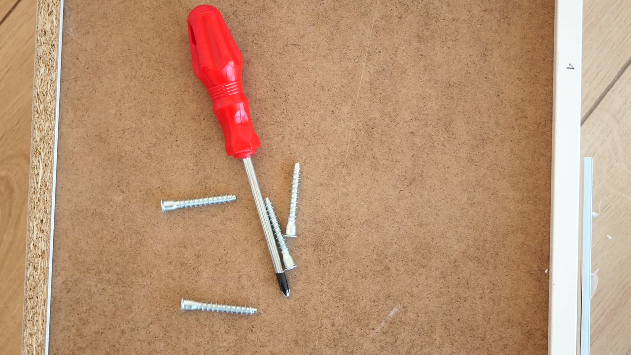 Furniture assembly tools and screws on a wooden board