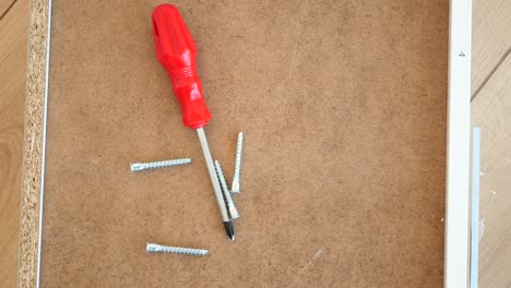 furniture assembly tools and screws on a wooden board