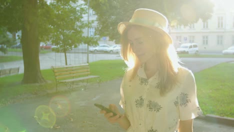 young woman using smartphone in the city park at sunrise.