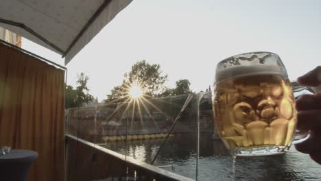 vasos de cerveza tintineando frente al puente de charles con puesta de sol en segundo plano