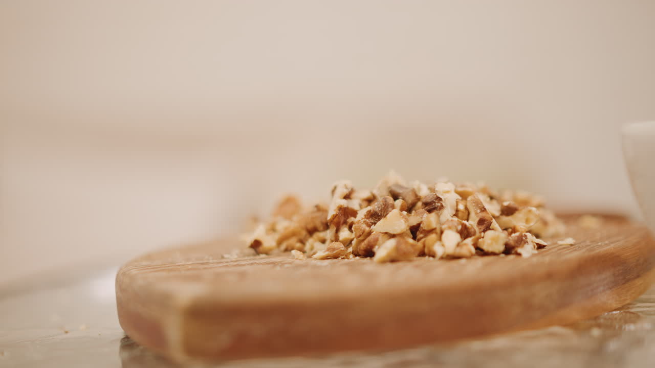 Preparazione della copertura di noci. Primo piano di granella di noci sopra la crosta di zucca in un ambiente caldo. Scena di cucina rustica con noci tritate sopra una crosta di torta di zucca appena sfornata con bokeh ambientale.