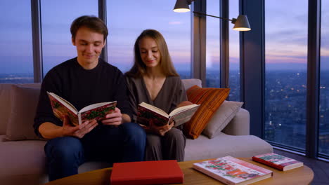 couple reading books in apartment with a city view