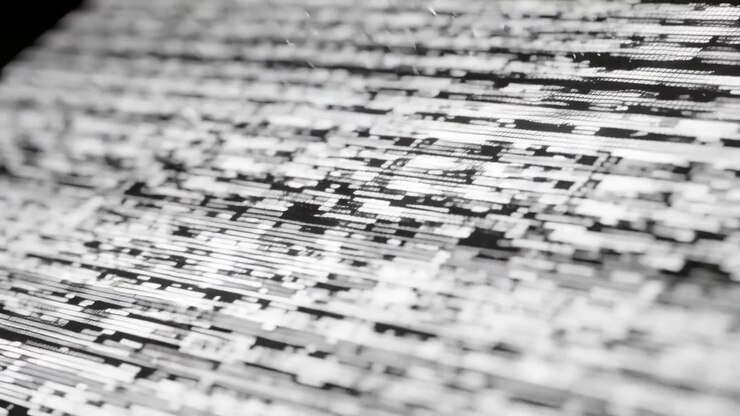 Un motivo di pixel glitchato che si sposta sulla superficie di un monitor, lo spostamento della messa a fuoco della telecamera fa ingrandire i blocchi
