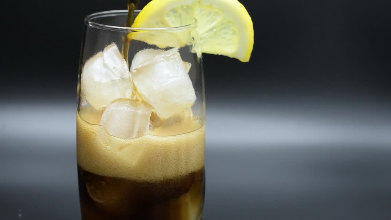 verter cola en un vaso con hielo y una rodaja de limón
