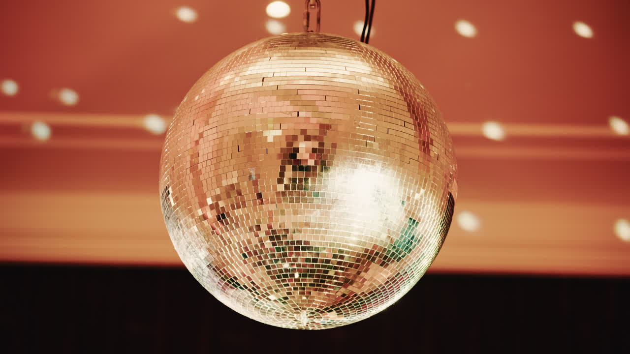 Bola de discoteca brilhante refletindo padrões de luz em um ambiente interno com iluminação quente