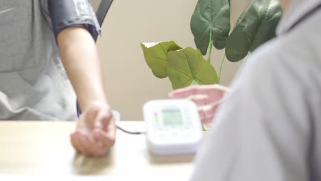 female doctor using digital tensimeter with stethoscope checking blood pressure to a patient in the hospital