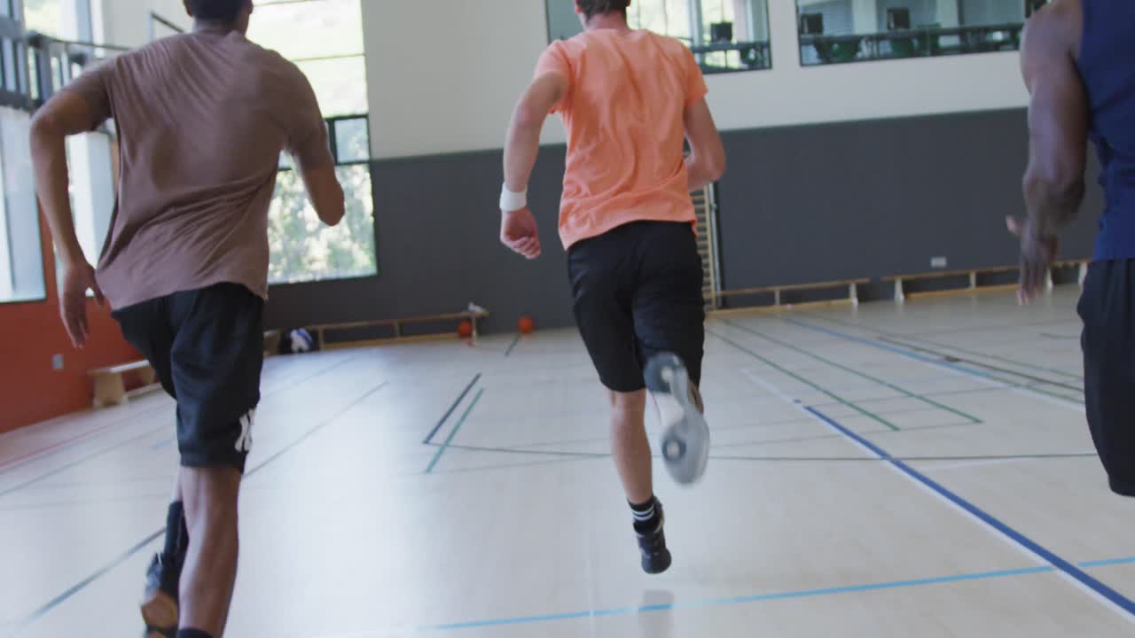 Diverse male basketball team and coach running and wearing sportswear