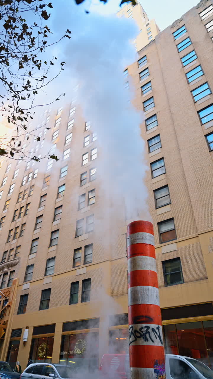 New York, USA, 18 dicembre 2025: Fumo bianco o vapore sale dal camino a strisce. Vista dal basso sugli edifici di New York, USA, sullo sfondo. Video verticale