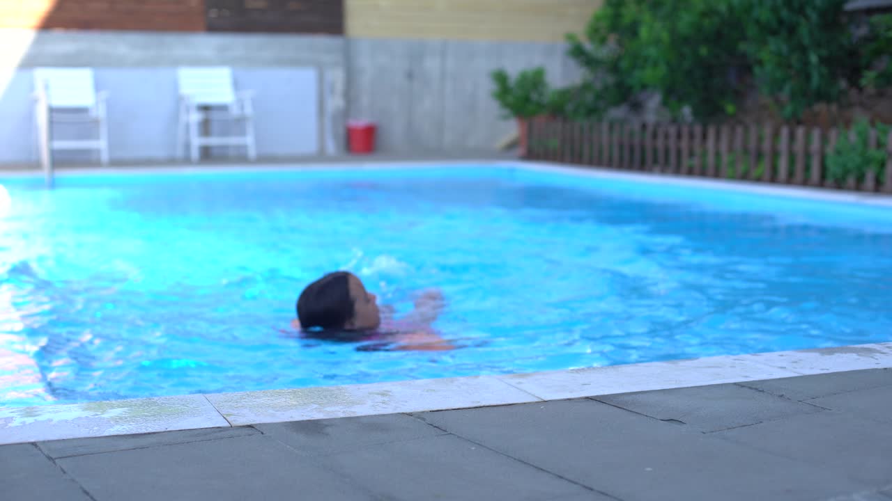 niña bonita nadando en la piscina al aire libre y divertirse con brazaletes inflables