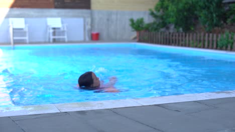 pretty little girl swimming in outdoor pool and have a fun with inflatable armbands