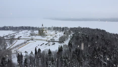 frozen white kaunas lagoon and pazaislis monastery covered in snow during heavy snowfall, aerial drone view