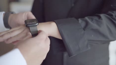 best man helping groom put on his watch on wedding day