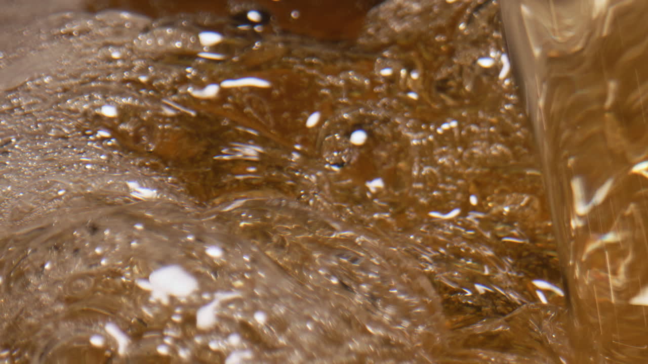 Fizzy cider foaming vessel closeup. Carbonated ale swirling establishing view