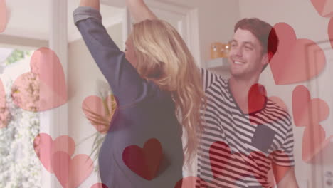 animation of hearts over happy diverse couple dancing at home