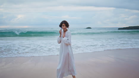 joyful girl speaking smartphone at ocean shore. carefree woman walking beach