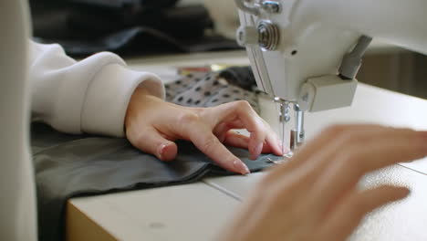 sewing machine needle in motion. close-up of sewing machine needle rapidly moves up and down. the tailor sews black fabric on the sewing workshop. the process of sewing fabric.