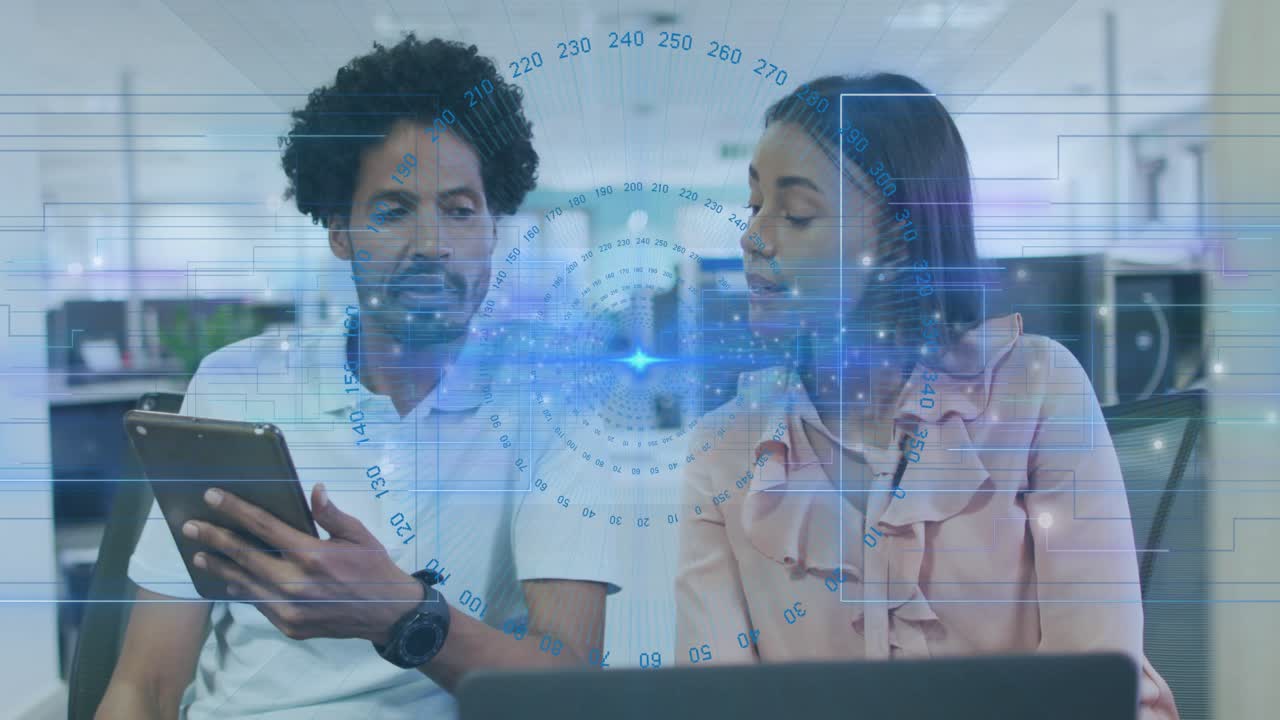 Colleagues interacting with tablet in office causing tech data charts for review on laptop