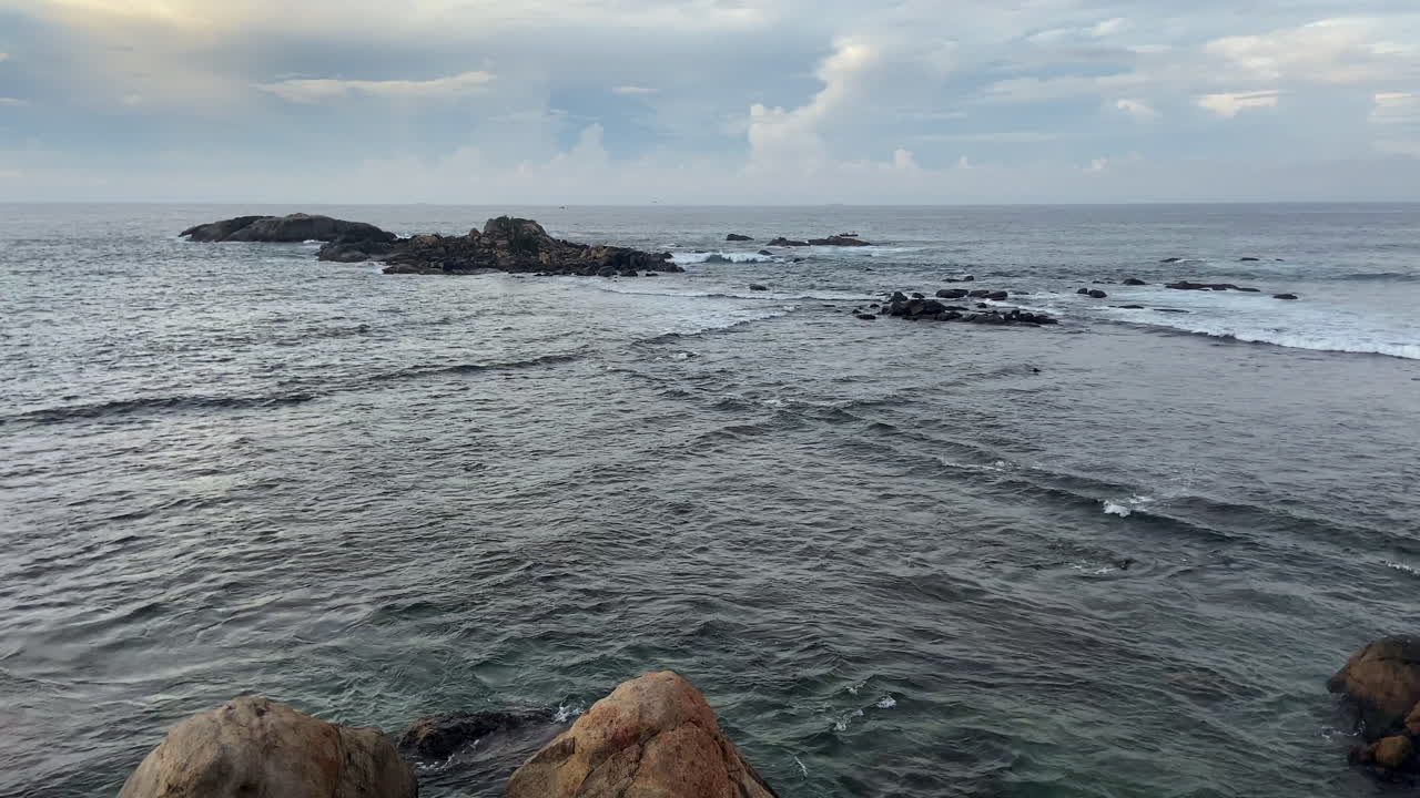 Establishing Handheld Static Shot Looking Out to Sea with Rocky Islands and Waves Coming from 2 Directions in Galle Sri Lanka