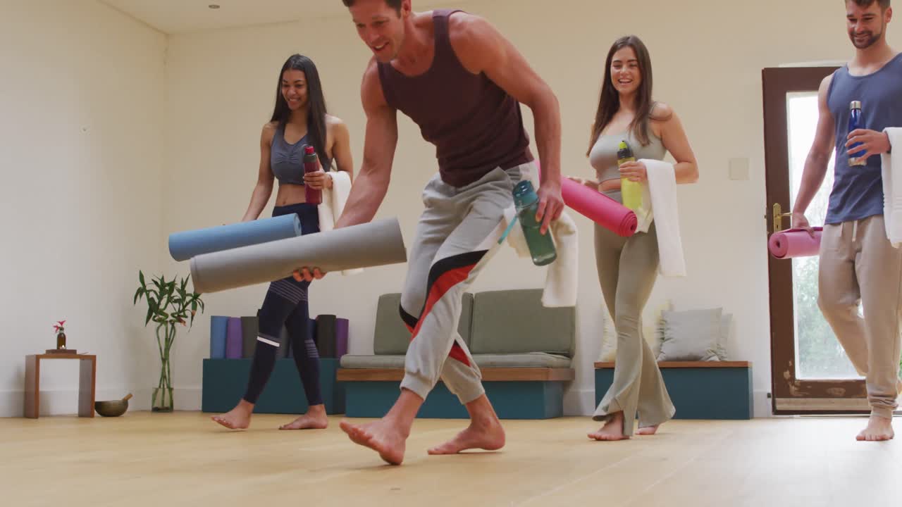 Diverse group unrolling mats for yoga class at studio with instructor