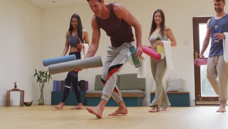 diverse group unrolling mats for yoga class at studio with instructor